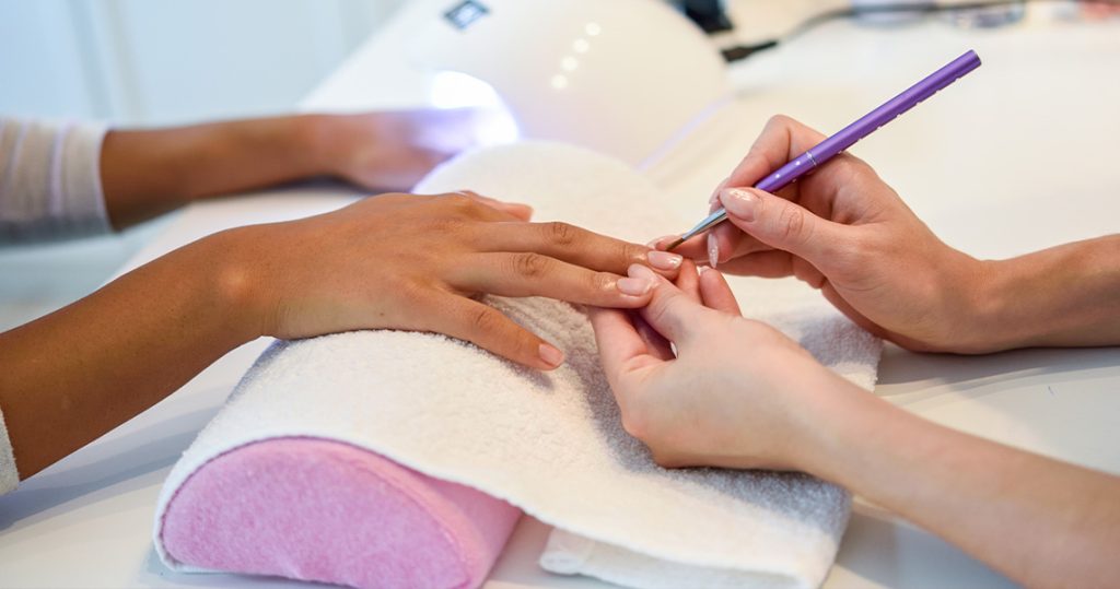 beauty therapist working on a woman's finger nails